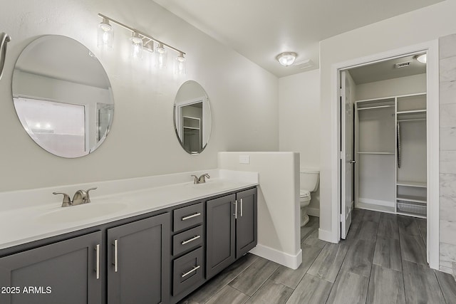 15360 N 87th Ave, Peoria, AZ 85381 - bathroom featuring toilet, baseboards, double vanity, wood finished floors, and a spacious closet