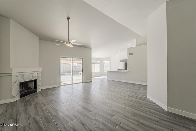 15360 N 87th Ave, Peoria, AZ 85381 - unfurnished living room featuring a ceiling fan, wood finished floors, a premium fireplace, baseboards, and a chandelier