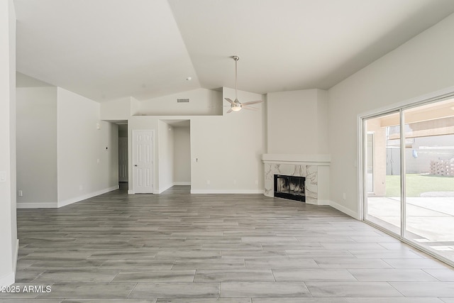 15360 N 87th Ave, Peoria, AZ 85381 - unfurnished living room featuring lofted ceiling, ceiling fan, a high end fireplace, light wood-style flooring, and baseboards