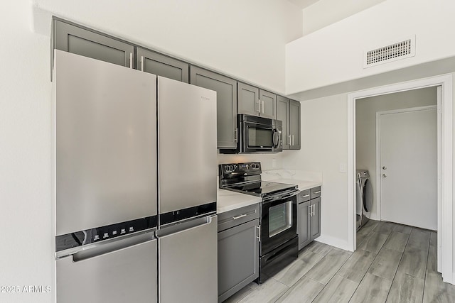 15360 N 87th Ave, Peoria, AZ 85381 - kitchen featuring black appliances, gray cabinetry, washer / dryer, light countertops, and wood finish floors
