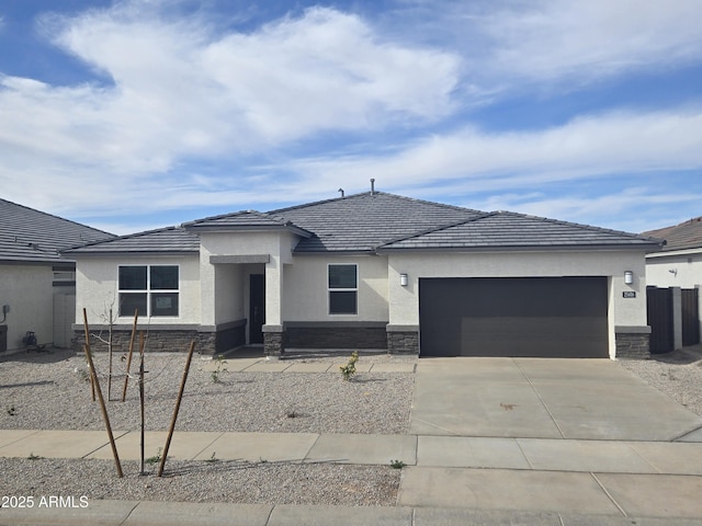 15389 W Cottontail Ln, Surprise, AZ 85387 - prairie-style home with stone siding, concrete driveway, and a garage