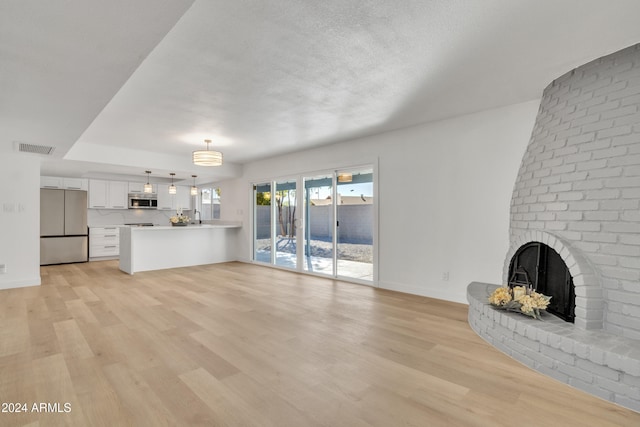 unfurnished living room featuring a fireplace, light hardwood / wood-style flooring, and a textured ceiling