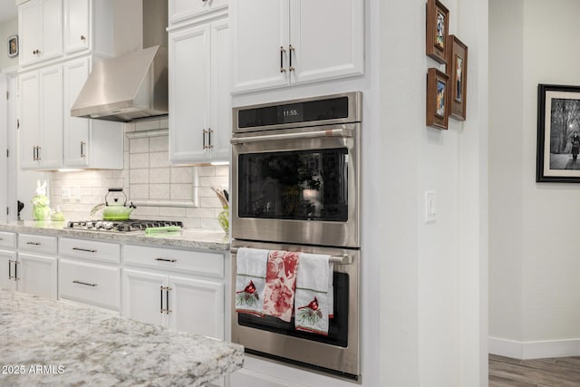 kitchen featuring white cabinetry, wall chimney range hood, and appliances with stainless steel finishes