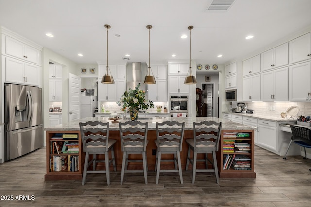 kitchen featuring light stone countertops, a kitchen island with sink, appliances with stainless steel finishes, and decorative light fixtures