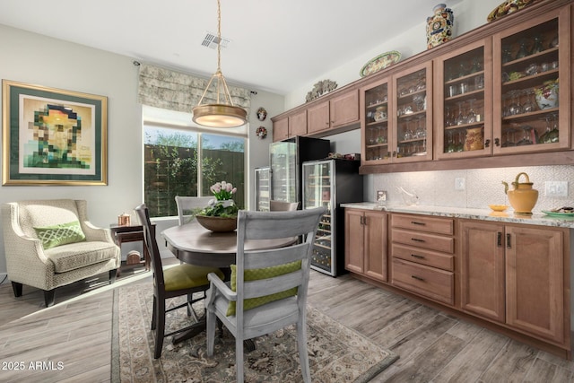 dining area featuring beverage cooler and light hardwood / wood-style flooring