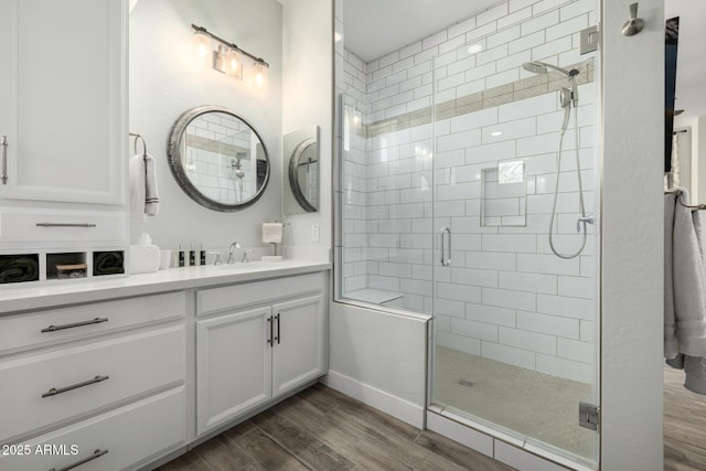 bathroom with a shower with shower door, wood-type flooring, and vanity