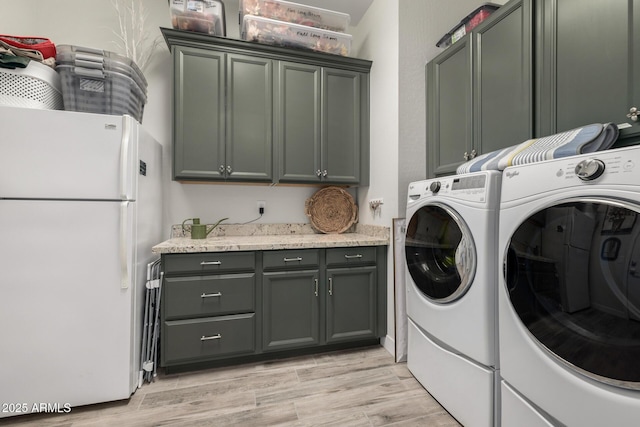 clothes washing area with washing machine and dryer and cabinets