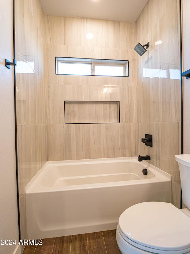 bathroom featuring hardwood / wood-style floors, toilet, and tiled shower / bath