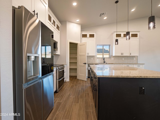 kitchen featuring pendant lighting, a center island, lofted ceiling, white cabinets, and appliances with stainless steel finishes