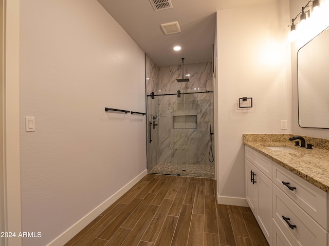 bathroom featuring vanity, a tile shower, and wood-type flooring