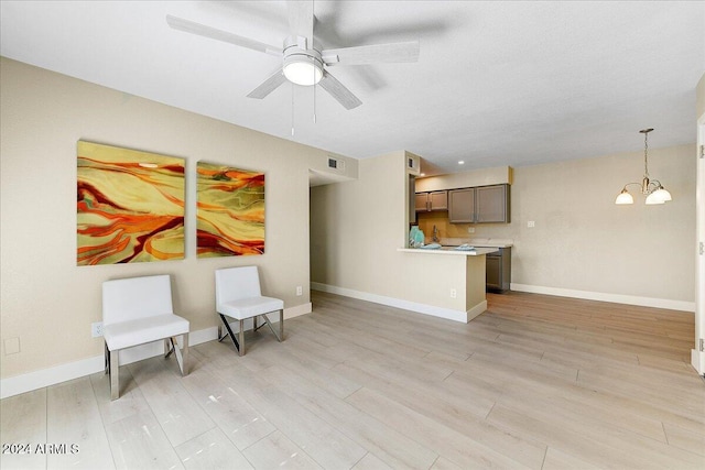 living area featuring ceiling fan with notable chandelier and light wood-type flooring