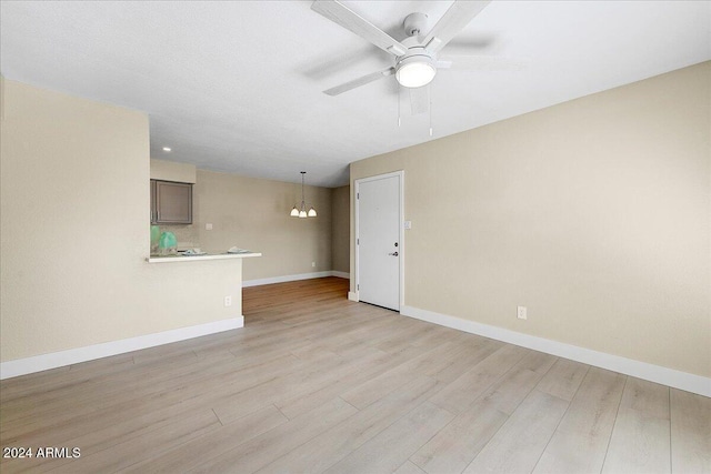 unfurnished room featuring light hardwood / wood-style flooring and ceiling fan with notable chandelier