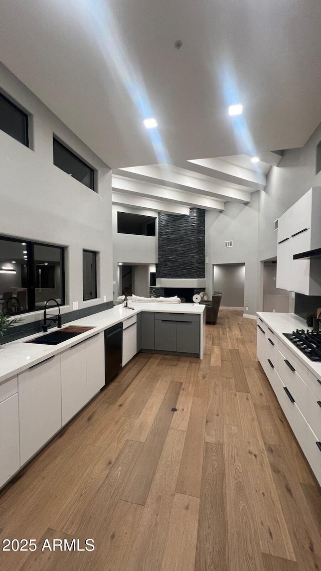 kitchen with light wood-style flooring, white cabinets, a sink, gas cooktop, and modern cabinets