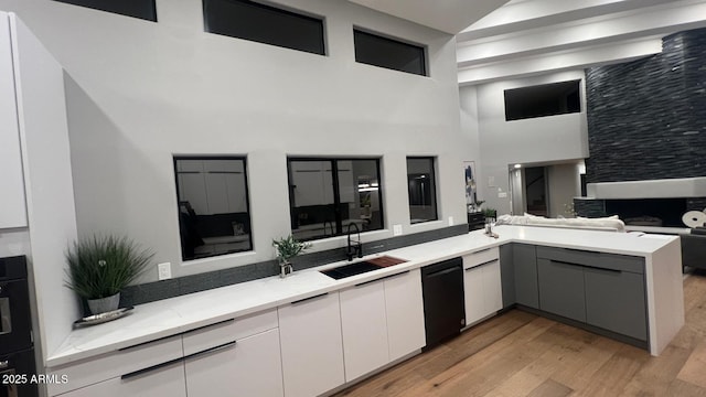 kitchen with sink, light hardwood / wood-style flooring, gray cabinets, light stone countertops, and kitchen peninsula