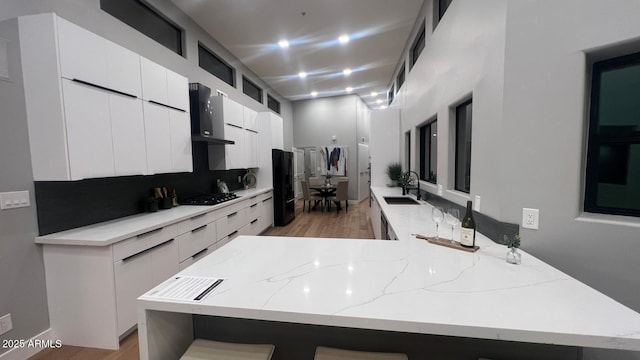 kitchen featuring sink, kitchen peninsula, white cabinets, light stone countertops, and black appliances