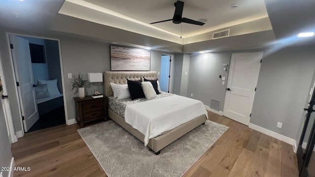 bedroom with a tray ceiling, hardwood / wood-style flooring, and ceiling fan