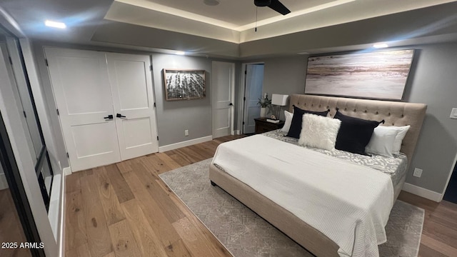 bedroom featuring a tray ceiling and light hardwood / wood-style flooring