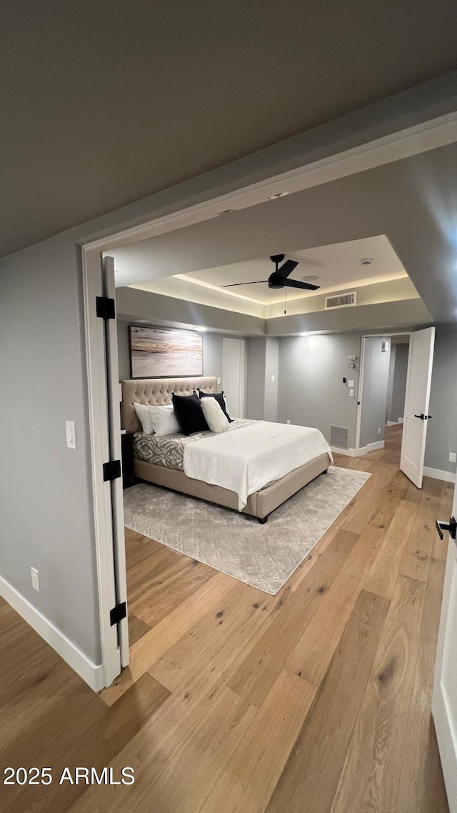 unfurnished bedroom with a tray ceiling and light wood-type flooring