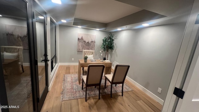 dining room featuring light wood-type flooring and a tray ceiling