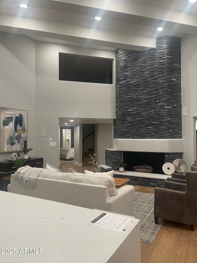 living room featuring a towering ceiling, a fireplace, and light wood-type flooring