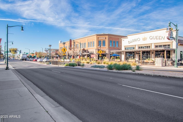 view of road featuring street lights, traffic signs, sidewalks, and curbs