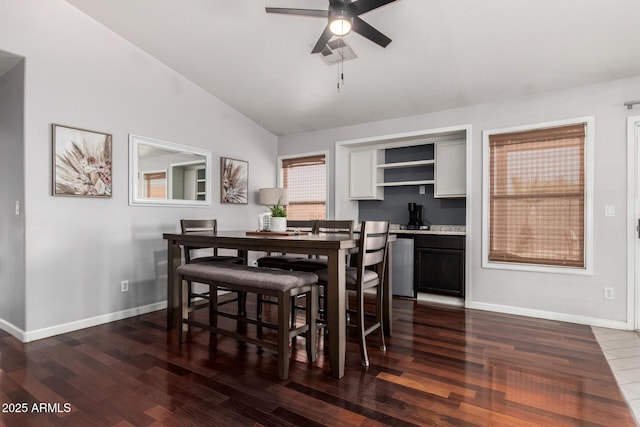dining space with baseboards, a ceiling fan, dark wood finished floors, and vaulted ceiling