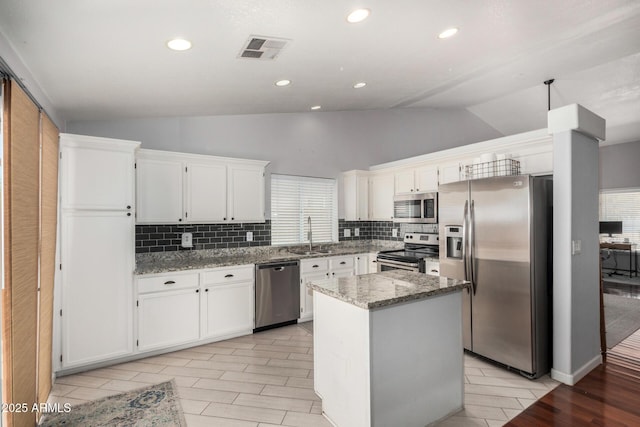 kitchen featuring visible vents, tasteful backsplash, vaulted ceiling, stone counters, and stainless steel appliances