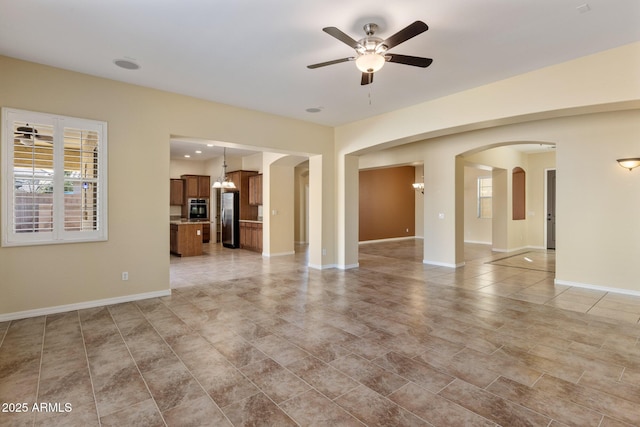 unfurnished living room featuring ceiling fan with notable chandelier