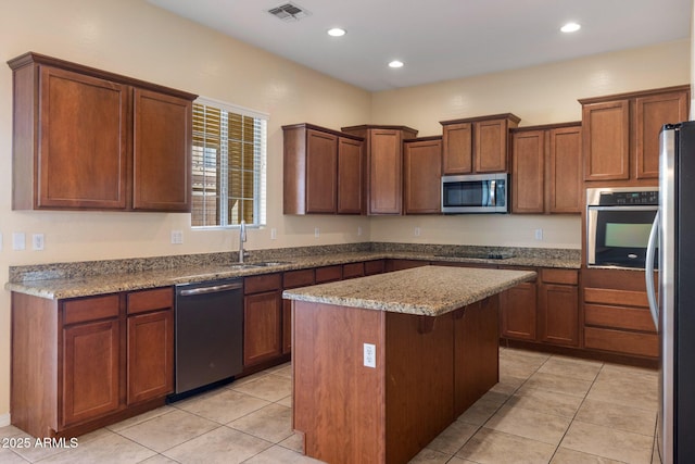 kitchen featuring appliances with stainless steel finishes, light stone countertops, a kitchen island, and light tile patterned floors