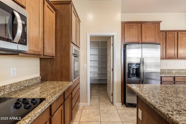 kitchen featuring stainless steel appliances, light stone countertops, and light tile patterned floors