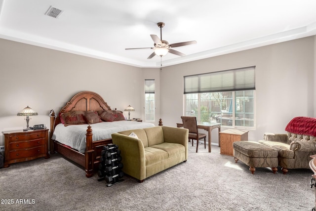 bedroom with carpet, a raised ceiling, visible vents, and a ceiling fan