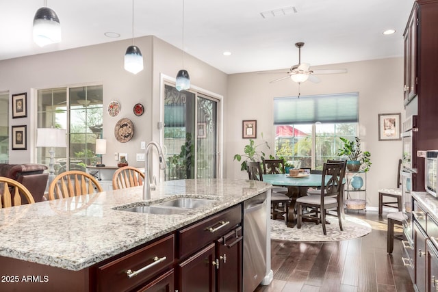 kitchen featuring dark wood-type flooring, a sink, visible vents, appliances with stainless steel finishes, and an island with sink