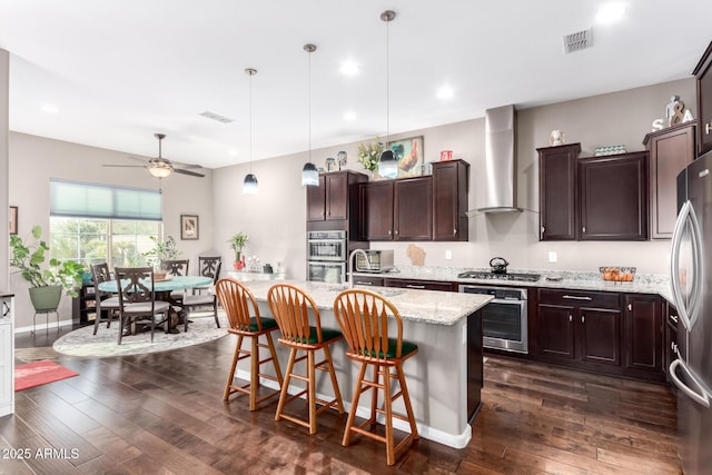 kitchen with appliances with stainless steel finishes, dark wood-style flooring, visible vents, and wall chimney exhaust hood