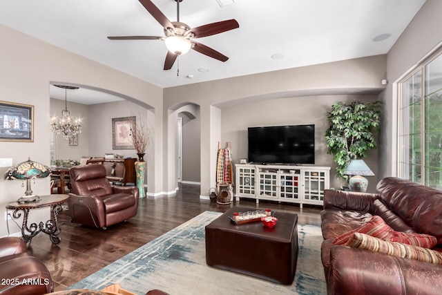 living room with arched walkways, ceiling fan with notable chandelier, wood finished floors, and baseboards