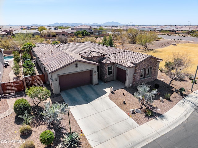 view of front facade with a tile roof, stucco siding, fence, a garage, and stone siding