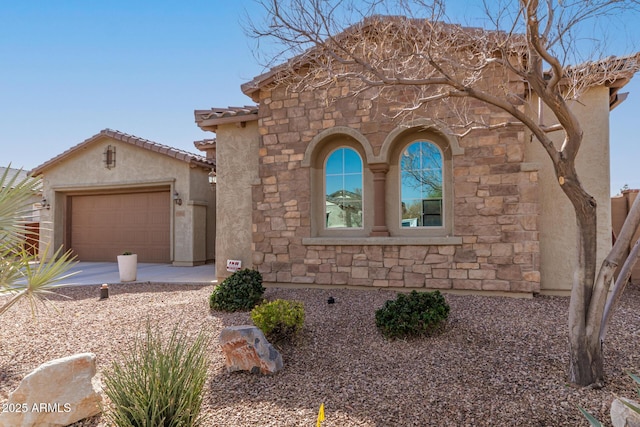 view of front of house with stone siding, a tiled roof, an attached garage, and stucco siding