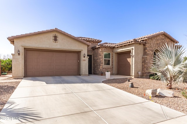 mediterranean / spanish home with an attached garage, a tile roof, concrete driveway, and stucco siding