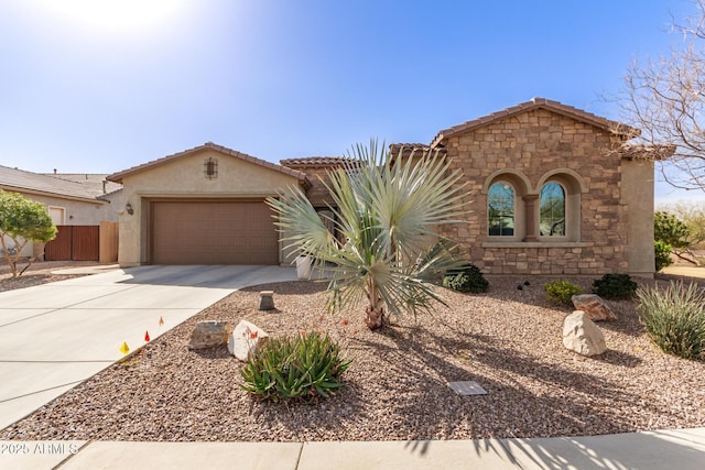 mediterranean / spanish-style house with stucco siding, concrete driveway, fence, a garage, and stone siding