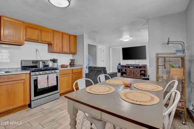 1815 E Illini St, Phoenix, AZ 85040 - kitchen with light countertops, backsplash, stainless steel range with gas stovetop, wood tiled floor, and a textured ceiling