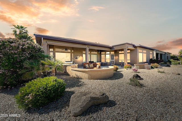20609 N Canyon Whisper Dr, Surprise, AZ 85387 - back of property at dusk featuring ceiling fan, a patio area, stucco siding, and an outdoor hangout area