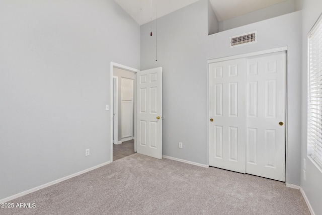 unfurnished bedroom with light carpet, high vaulted ceiling, and a closet