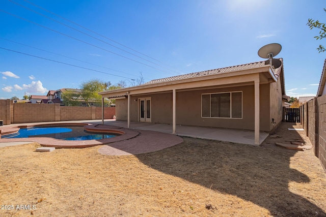 back of property with a fenced in pool and a patio area