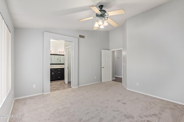 unfurnished bedroom featuring connected bathroom, vaulted ceiling, light carpet, a closet, and ceiling fan