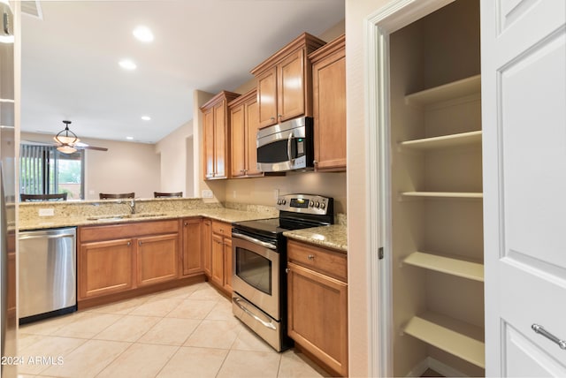 kitchen with sink, light stone countertops, light tile patterned floors, appliances with stainless steel finishes, and ceiling fan