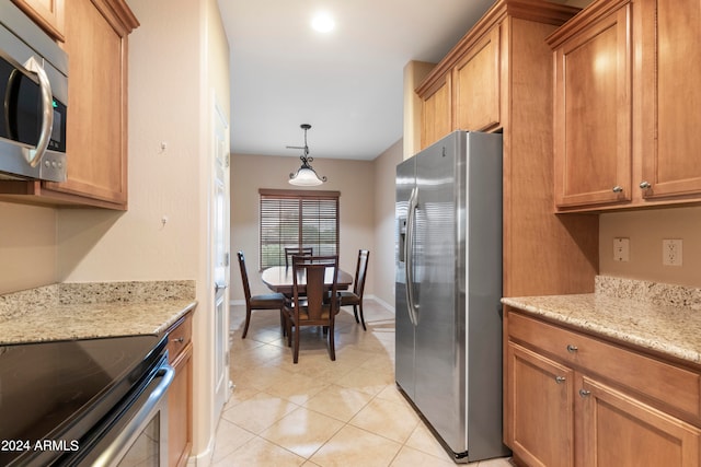 kitchen featuring decorative light fixtures, light stone countertops, stainless steel appliances, and light tile patterned floors