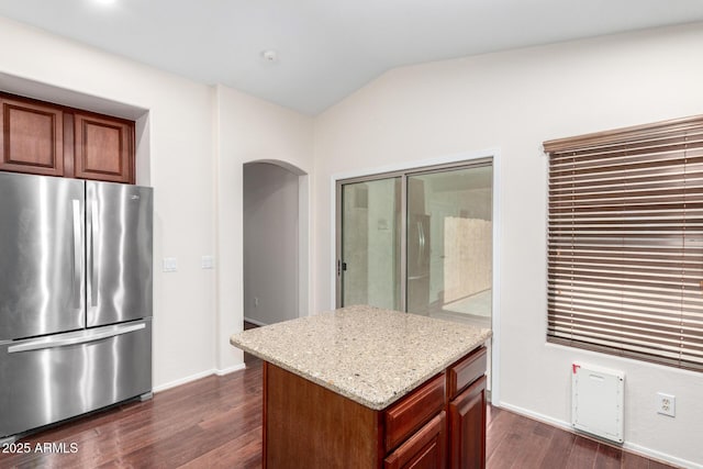 12838 W Desert Mirage Dr, Peoria, AZ 85383 - kitchen with dark wood-style flooring, light stone countertops, arched walkways, freestanding refrigerator, and lofted ceiling