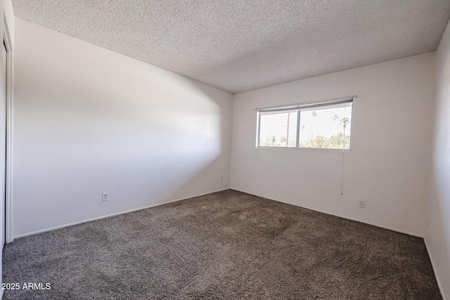 unfurnished room with dark carpet and a textured ceiling