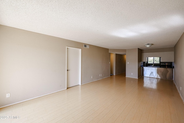 spare room featuring a textured ceiling and light wood-type flooring