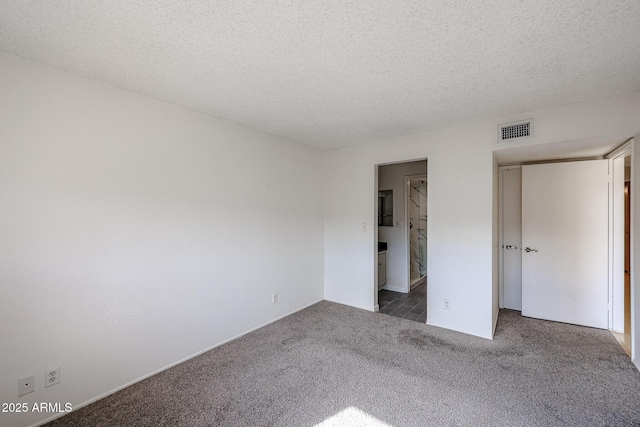 unfurnished bedroom with connected bathroom, dark carpet, and a textured ceiling