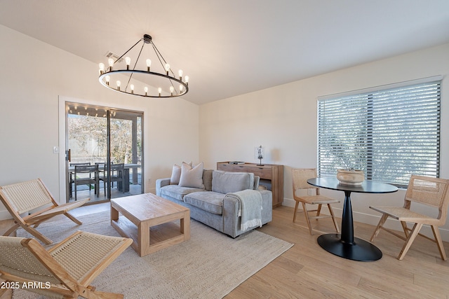 living room with light hardwood / wood-style floors and a notable chandelier